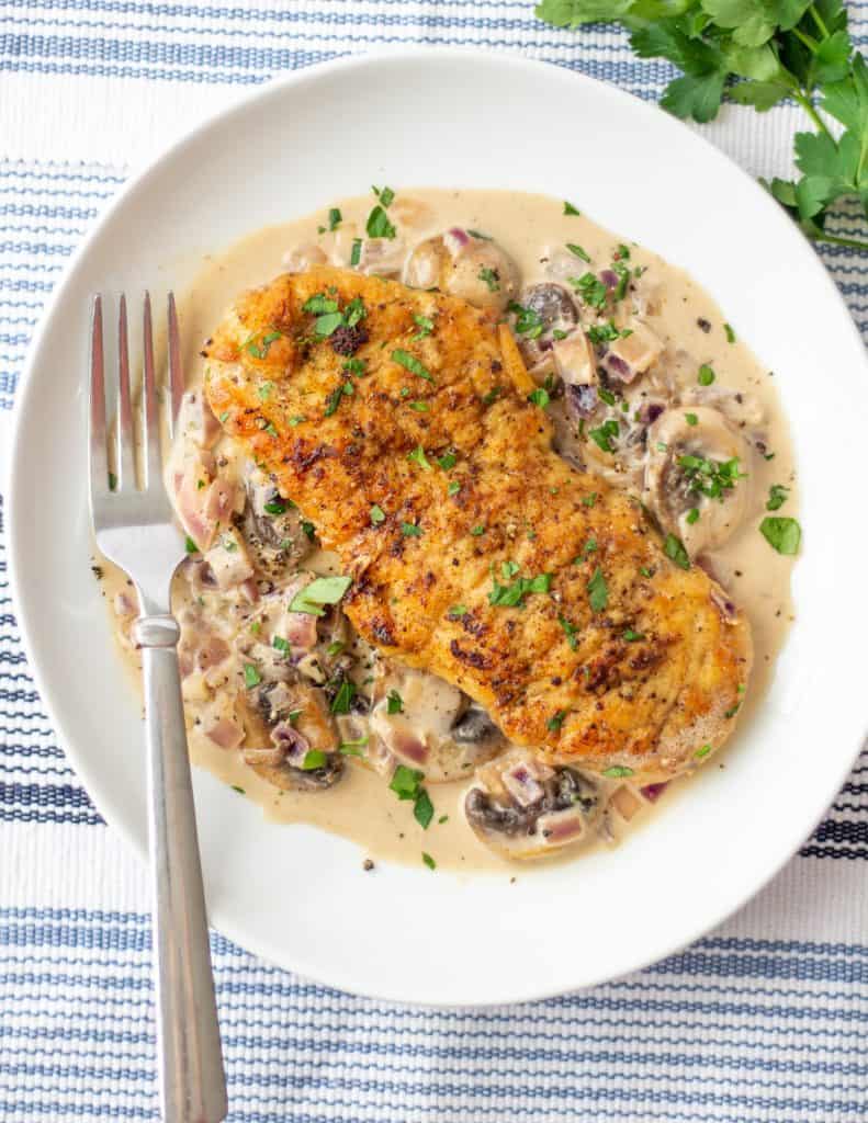 chicken with sauce on a small plate with a fork