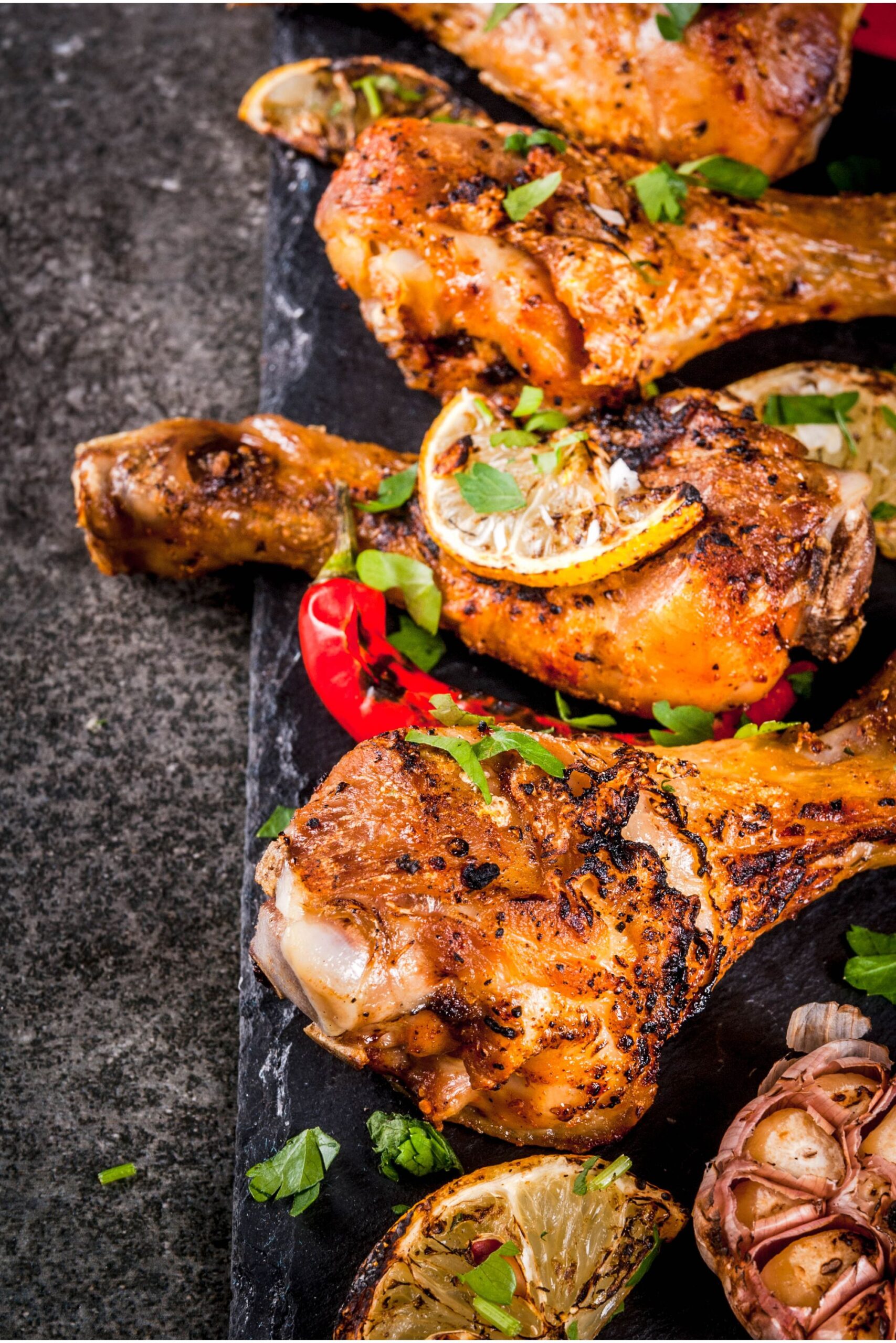 grilled chicken drumsticks on a black plate